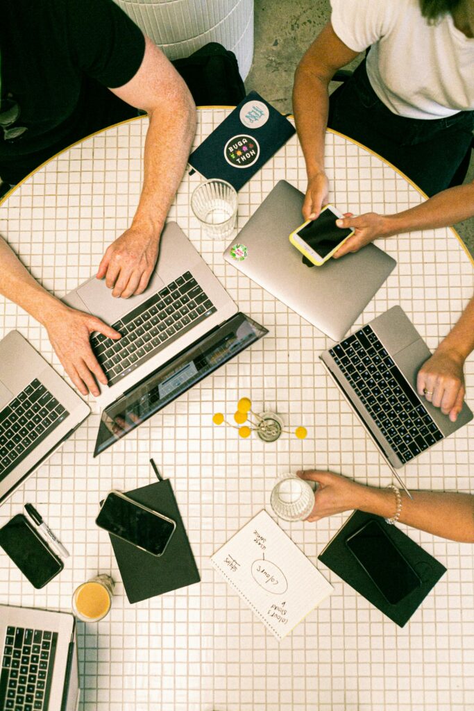stock_services1 Top view of a team collaborating with laptops, phones, and notes in a modern office.